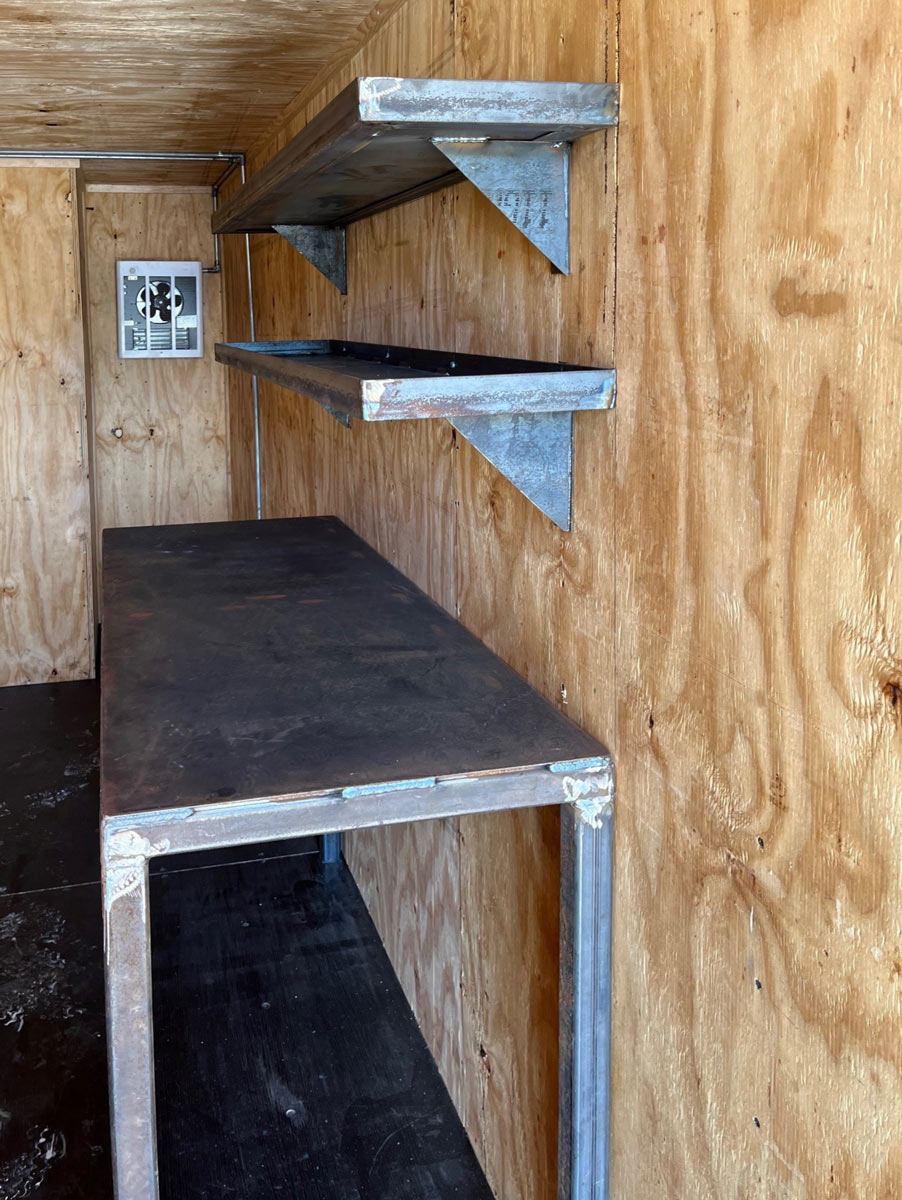 container with wood paneling, fan, metal shelves and table