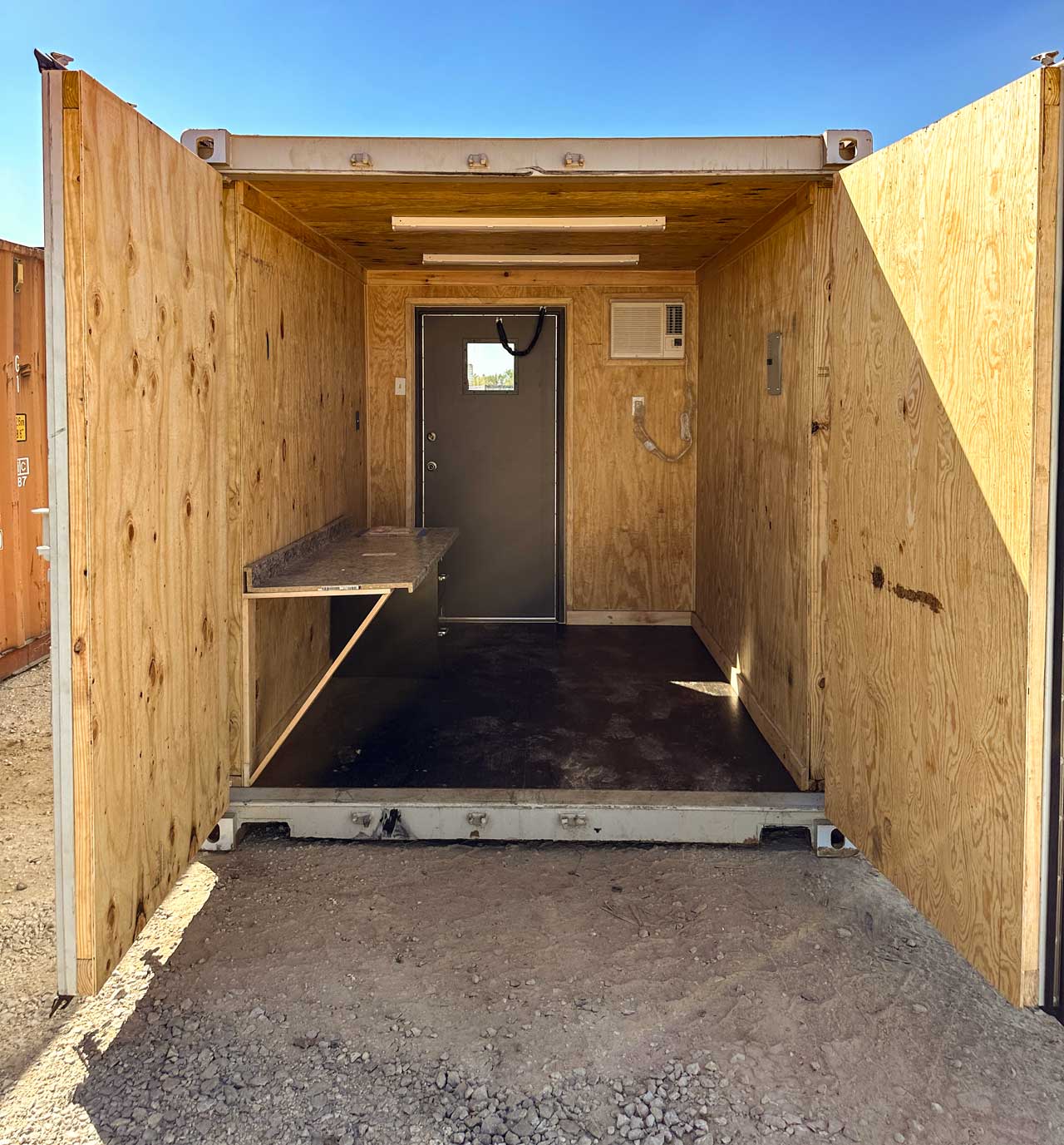 container with wood panel walls, a/c, desk and man door